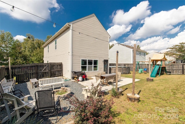 rear view of house featuring a playground, a lawn, a patio, and an outdoor fire pit