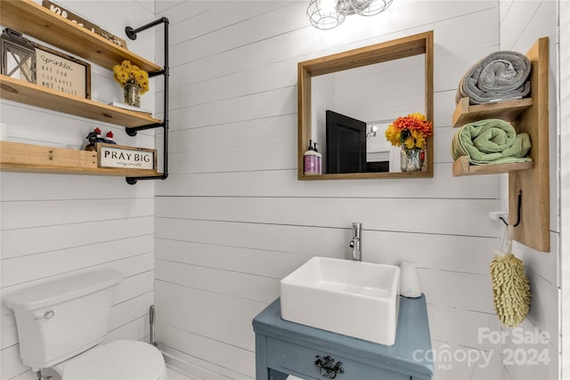 bathroom featuring wood walls, vanity, and toilet