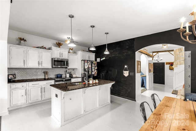 kitchen with backsplash, a center island with sink, sink, appliances with stainless steel finishes, and white cabinetry