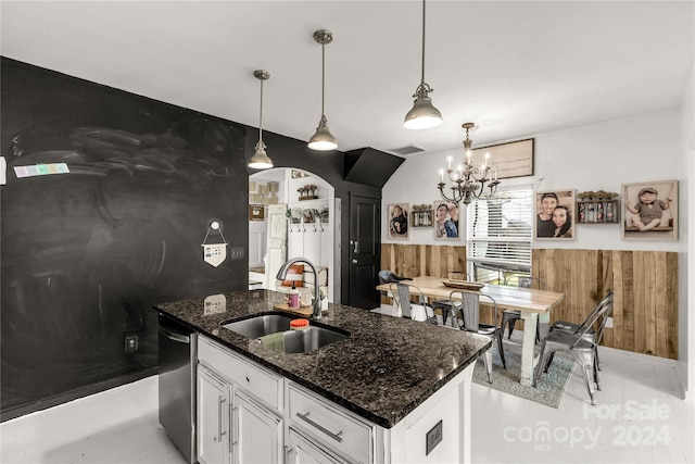 kitchen with white cabinetry, sink, dishwasher, dark stone countertops, and a kitchen island with sink