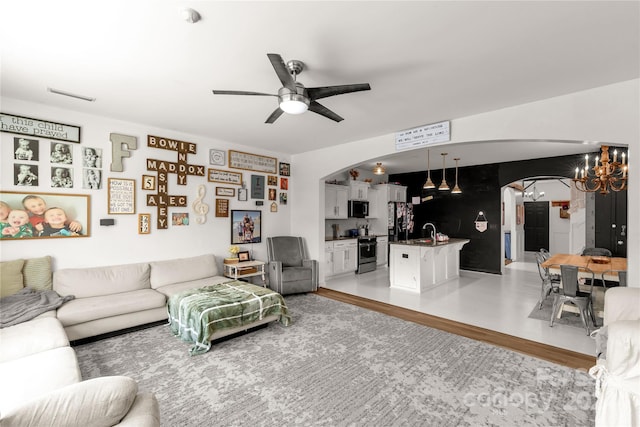 living room with sink, light hardwood / wood-style floors, and ceiling fan with notable chandelier