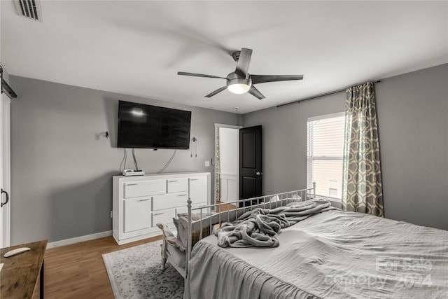 bedroom with a barn door, light hardwood / wood-style flooring, and ceiling fan