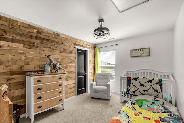 bedroom with carpet flooring, wooden walls, and a crib