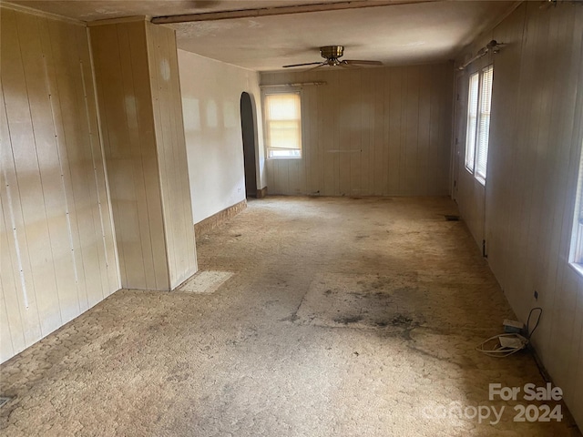 empty room with ceiling fan and wooden walls