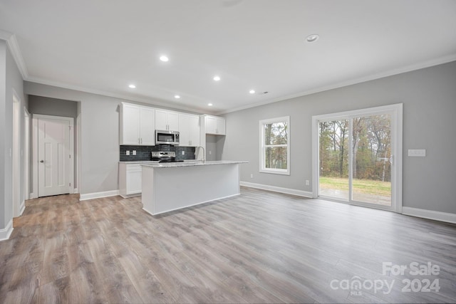 kitchen with a kitchen island with sink, ornamental molding, light hardwood / wood-style floors, white cabinetry, and stainless steel appliances