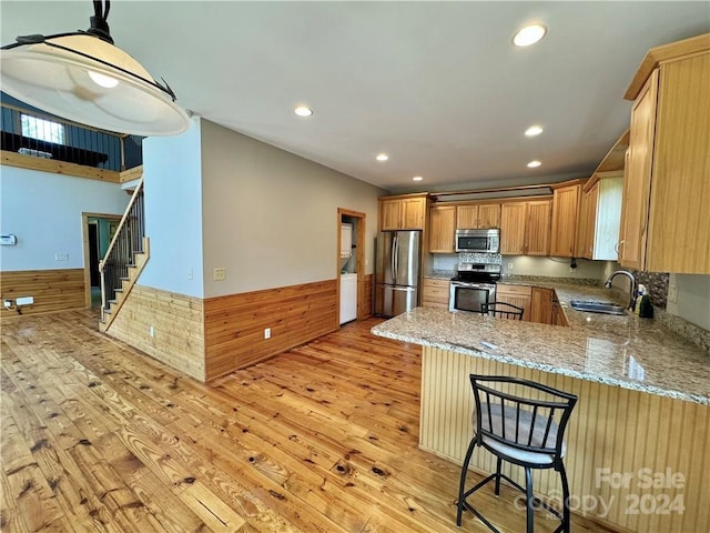 kitchen featuring light hardwood / wood-style floors, sink, kitchen peninsula, and stainless steel appliances