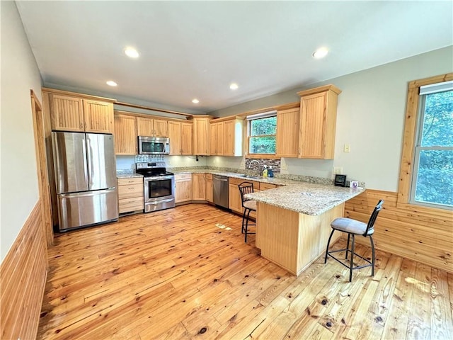 kitchen with kitchen peninsula, appliances with stainless steel finishes, plenty of natural light, and a breakfast bar area