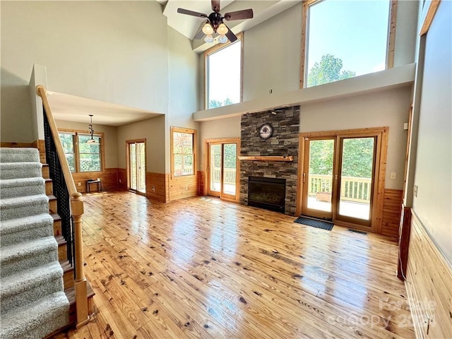 unfurnished living room with plenty of natural light, ceiling fan, high vaulted ceiling, and light hardwood / wood-style flooring