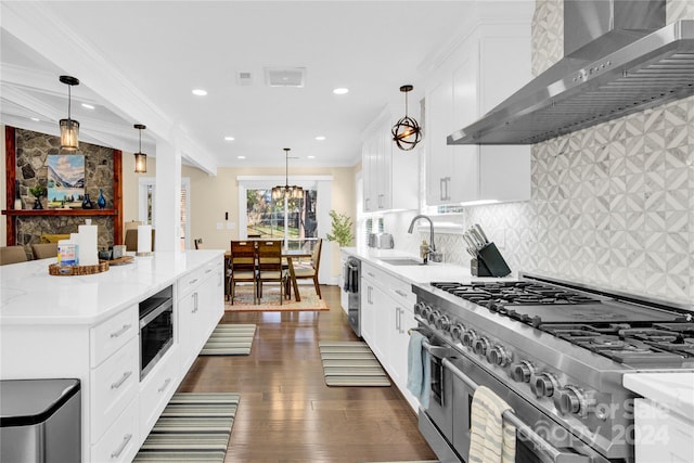 kitchen featuring backsplash, pendant lighting, stainless steel appliances, and wall chimney range hood