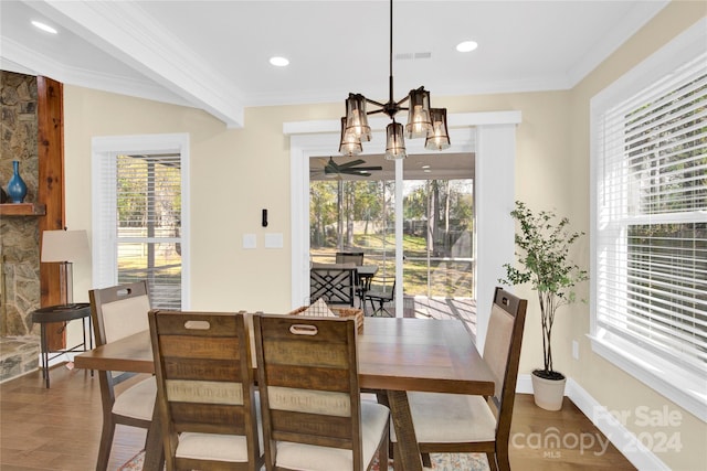 dining room with wood-type flooring, ornamental molding, and a healthy amount of sunlight