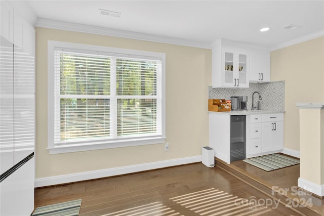 kitchen with dark wood-type flooring, black dishwasher, crown molding, decorative backsplash, and white cabinets