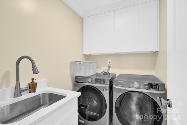 washroom featuring cabinets, washer and clothes dryer, ornamental molding, and sink