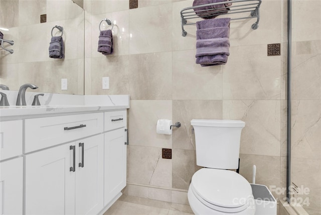 bathroom featuring tile patterned floors, vanity, toilet, and tile walls