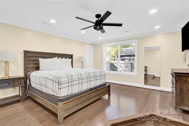 bedroom featuring hardwood / wood-style flooring, ceiling fan, and crown molding