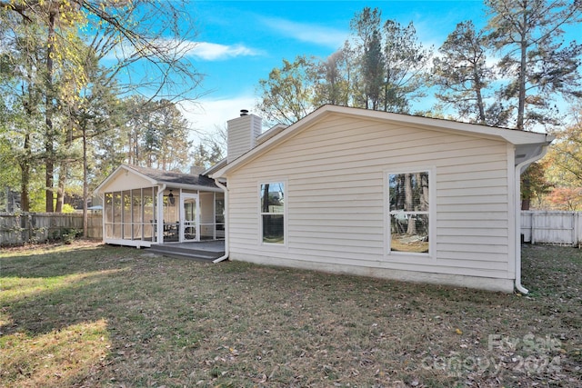 back of property featuring a lawn and a sunroom