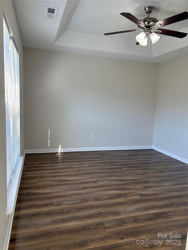 spare room featuring dark hardwood / wood-style floors, a raised ceiling, and a textured ceiling