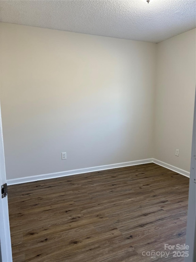 empty room featuring dark wood-type flooring and a textured ceiling