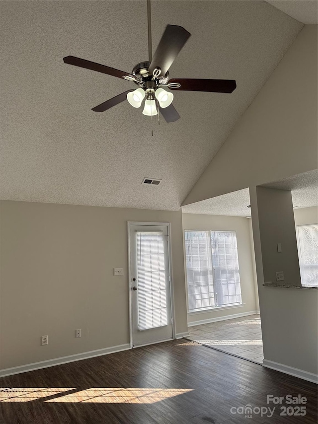 doorway with ceiling fan, dark hardwood / wood-style flooring, a textured ceiling, and high vaulted ceiling