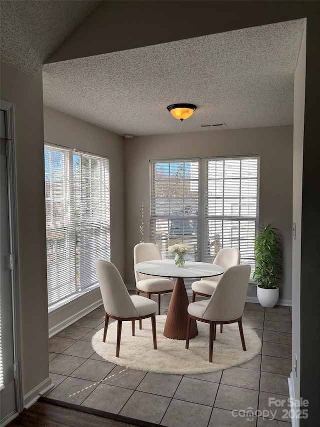 tiled dining room with a textured ceiling and vaulted ceiling