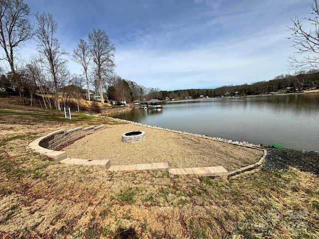 surrounding community featuring a fire pit and a water view