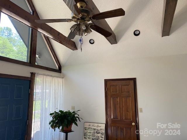 entryway featuring lofted ceiling with beams, ceiling fan, and a textured ceiling