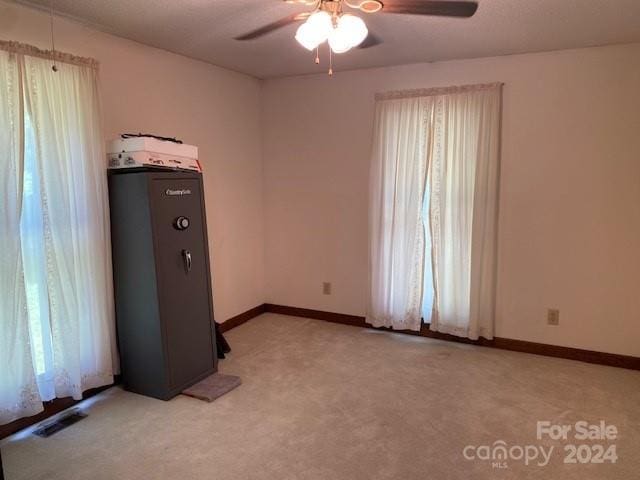 carpeted spare room featuring ceiling fan and a healthy amount of sunlight