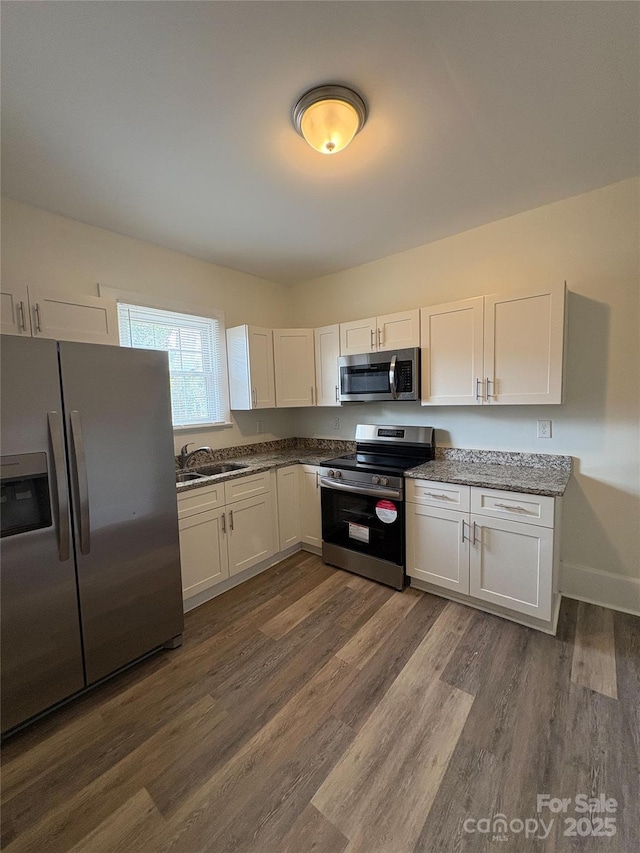 kitchen featuring a sink, dark wood-type flooring, appliances with stainless steel finishes, and white cabinets