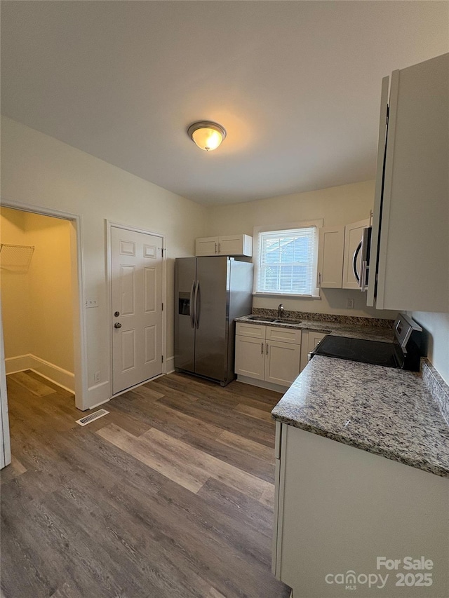 kitchen featuring visible vents, dark wood-type flooring, a sink, white cabinetry, and appliances with stainless steel finishes