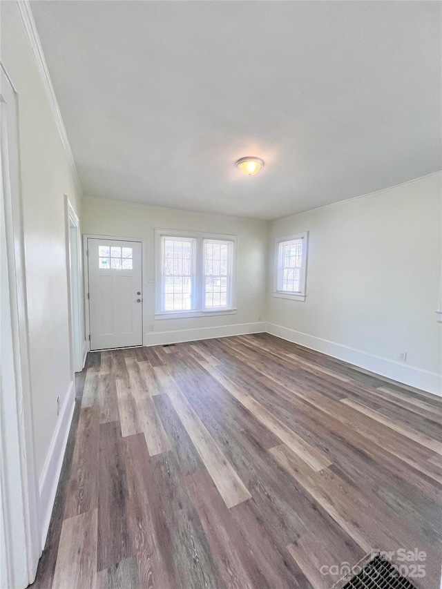 unfurnished living room with baseboards, wood finished floors, and crown molding