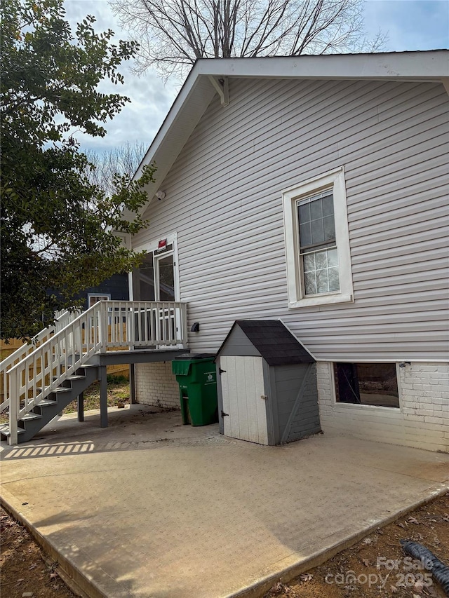 back of property with an outbuilding, a patio area, and a shed