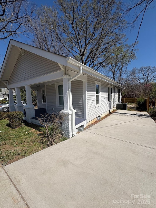 view of side of home featuring a porch, central AC, and driveway