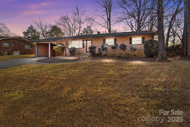 view of front of house with driveway, crawl space, a lawn, and brick siding