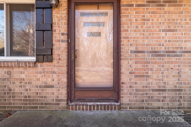 view of exterior entry with brick siding