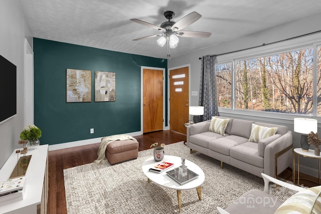 living area featuring wood finished floors, a ceiling fan, and baseboards