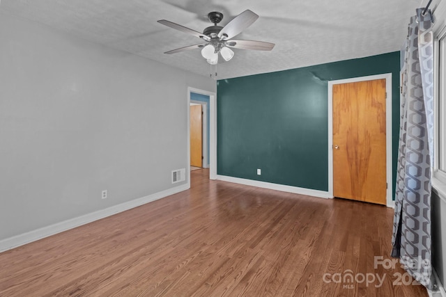 unfurnished room with a ceiling fan, baseboards, visible vents, and wood finished floors