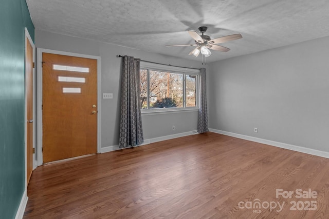 interior space featuring ceiling fan, a textured ceiling, baseboards, and wood finished floors