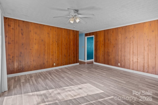 spare room with crown molding, baseboards, ceiling fan, and wood finished floors