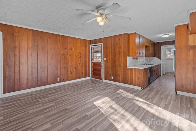 kitchen with wood finished floors, a sink, black dishwasher, light countertops, and brown cabinetry