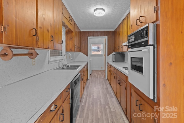 kitchen with light countertops, brown cabinets, a sink, and black appliances