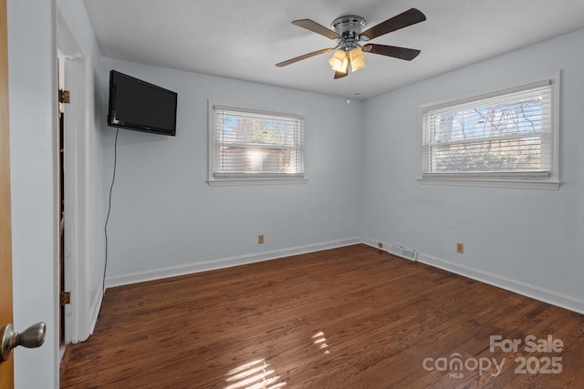 empty room with dark wood-type flooring, visible vents, ceiling fan, and baseboards