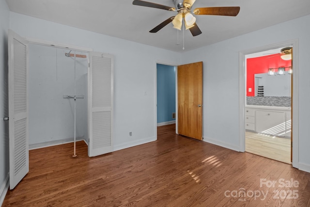 unfurnished bedroom with ceiling fan, connected bathroom, wood finished floors, baseboards, and a closet