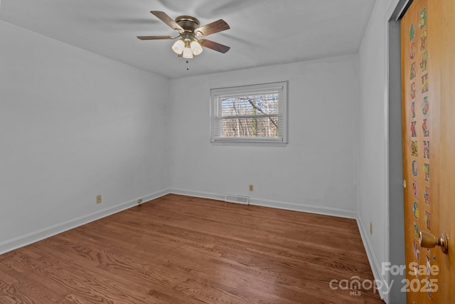 unfurnished room with a ceiling fan, wood finished floors, visible vents, and baseboards