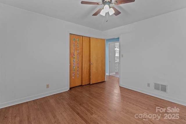 spare room with baseboards, visible vents, ceiling fan, and wood finished floors