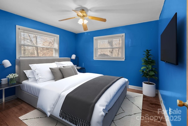 bedroom with ceiling fan, wood finished floors, and baseboards