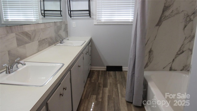 bathroom featuring double vanity, wood finished floors, a sink, and visible vents