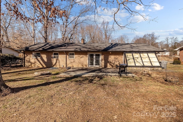 back of house featuring brick siding, a yard, french doors, a chimney, and a patio area