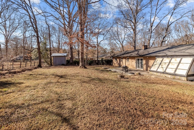 view of yard featuring an outbuilding, a shed, and fence