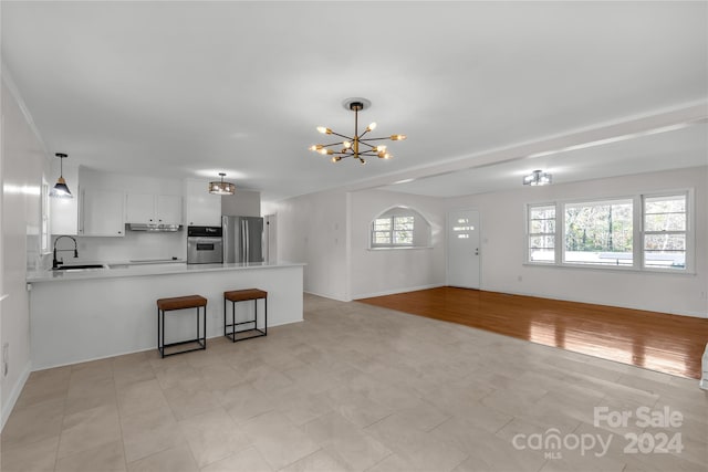 kitchen featuring sink, kitchen peninsula, light hardwood / wood-style flooring, white cabinetry, and stainless steel appliances