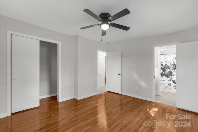 unfurnished bedroom featuring ensuite bath, ceiling fan, a closet, and hardwood / wood-style flooring