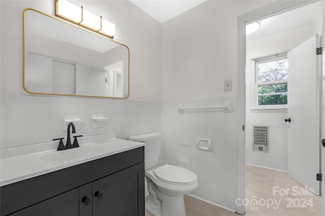 bathroom with tile patterned flooring, vanity, heating unit, and tile walls